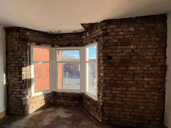 Bay window wall stripped back to damp brick